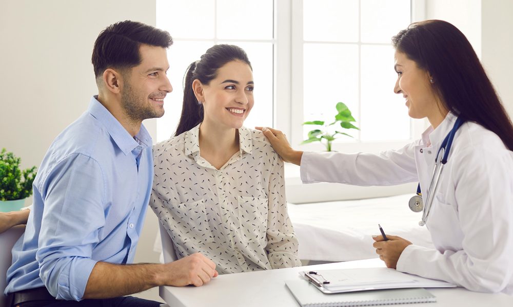 Female doctor consulting young couple patients in fertility clinic about IVF or IUI. Doctor encourages and assures the young couple that everything will be fine. Concept of artificial insemination.